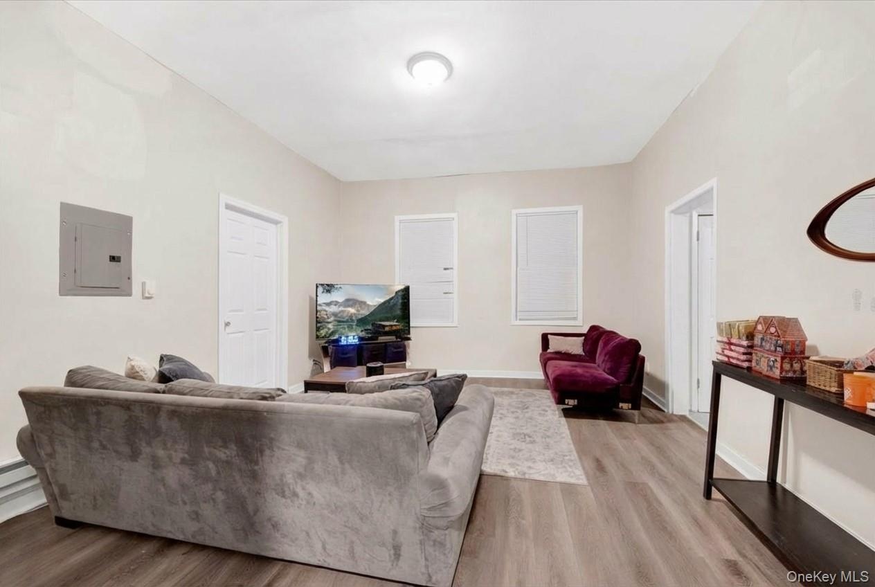 Living area with electric panel and light wood-type flooring