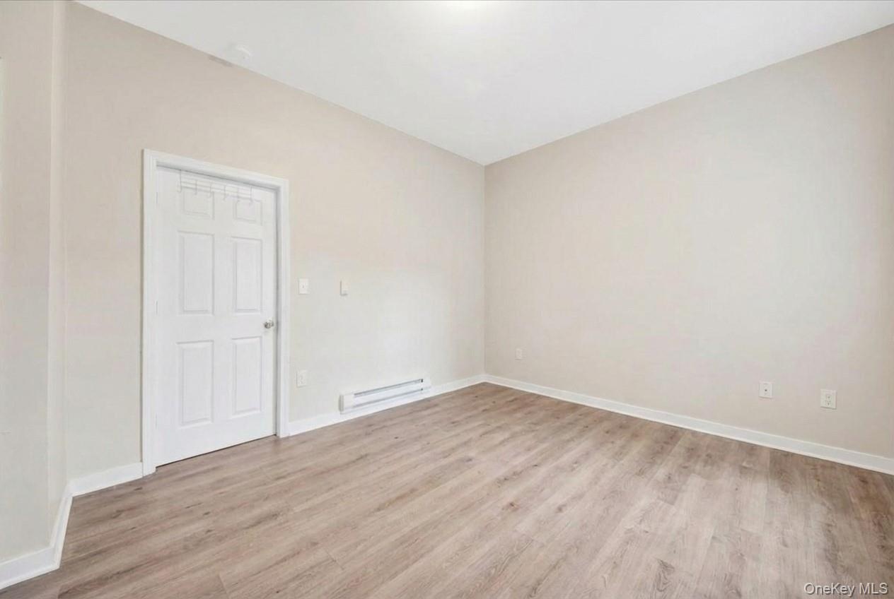 Bedroom with light wood-style floors and a baseboard heating unit