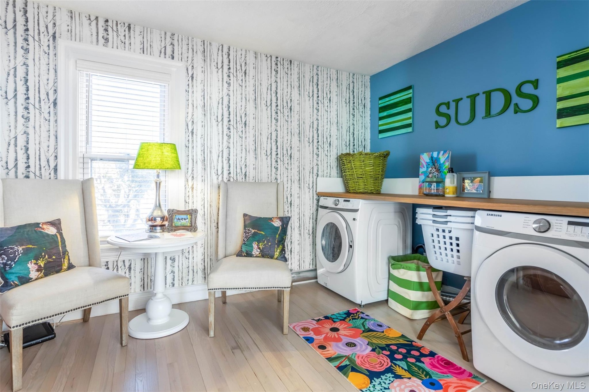 Laundry room featuring wood-type flooring, washing machine and clothes dryer, and wallpapered walls