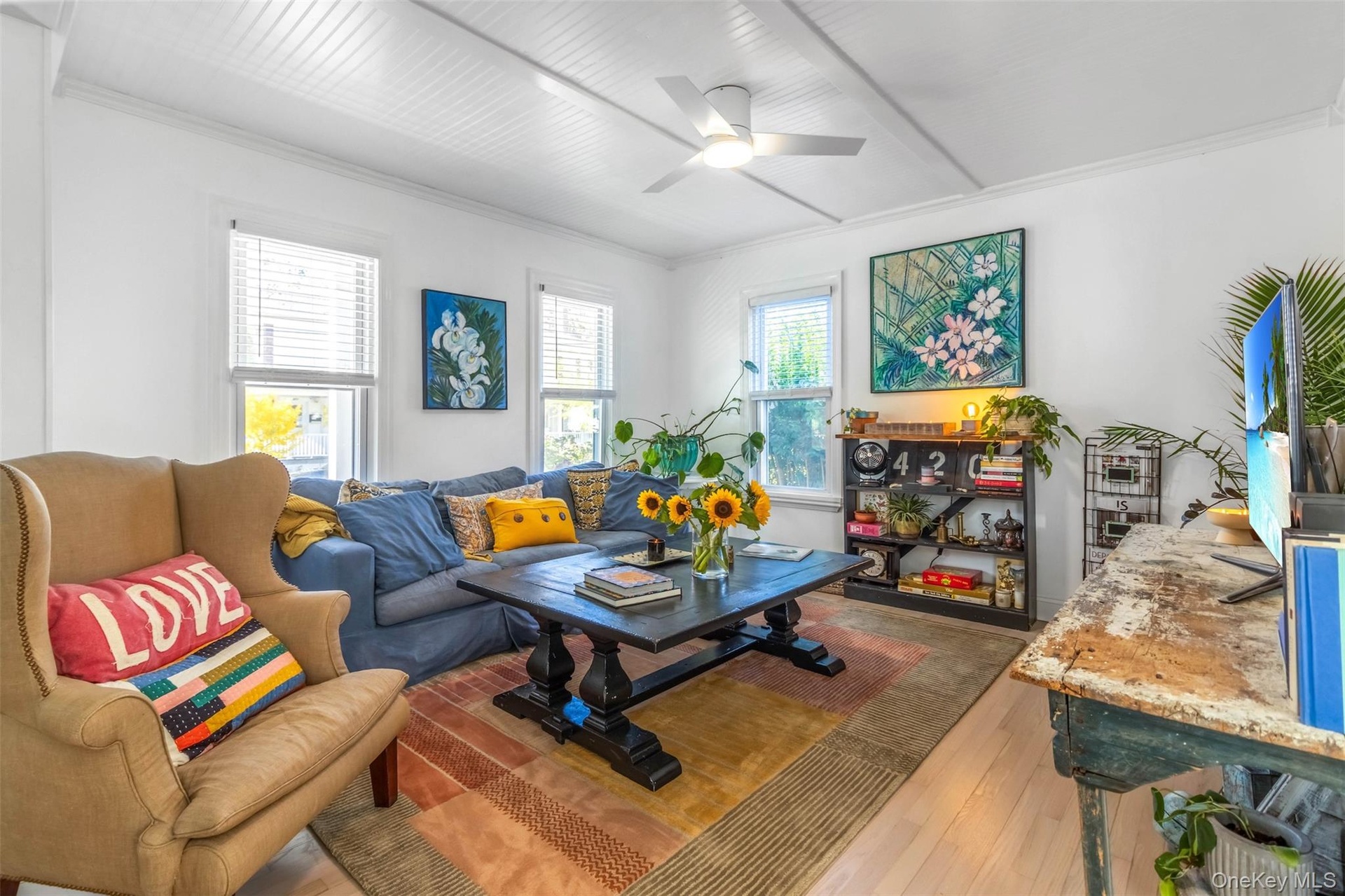 Living room with light wood-style floors, ceiling fan, and ornamental molding