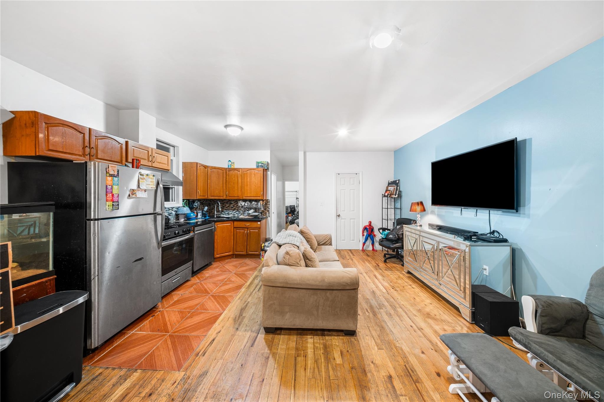 Kitchen featuring open floor plan, stainless steel appliances, backsplash, brown cabinets, and dark countertops