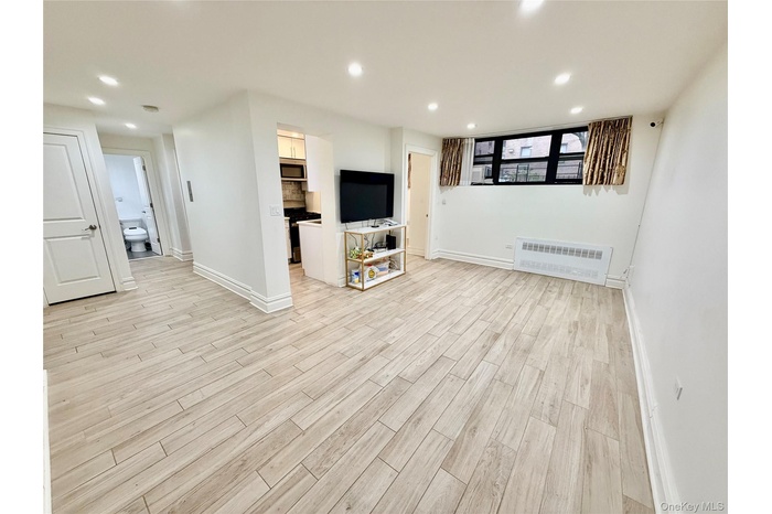 Basement featuring radiator heating unit, recessed lighting, and light wood finished floors