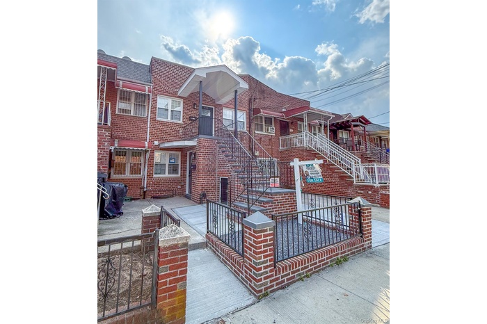 View of front of home featuring brick siding, a gate, a fenced front yard, and stairs