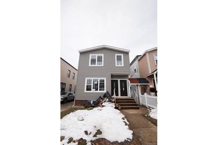 Two-story property featuring light gray horizontal siding and a gable roof