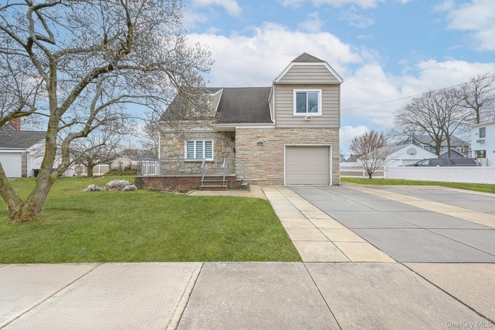 View of front facade featuring stone siding, driveway, an attached garage, and roof with shingles