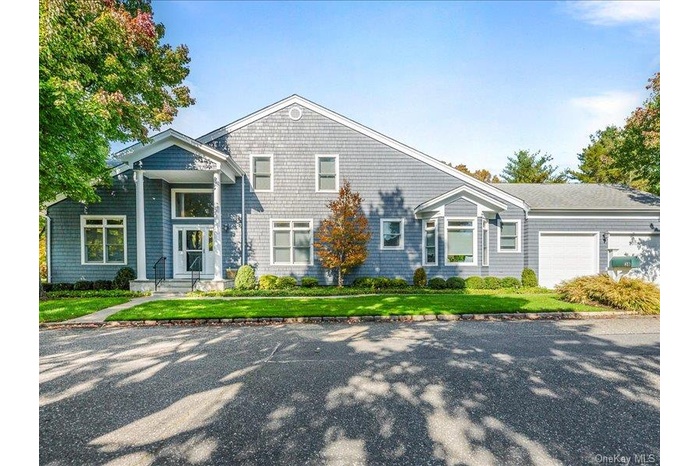 Shingle-style home featuring a front lawn and a garage