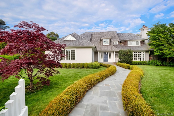 View of front of home featuring a front lawn, a chimney, and stucco siding