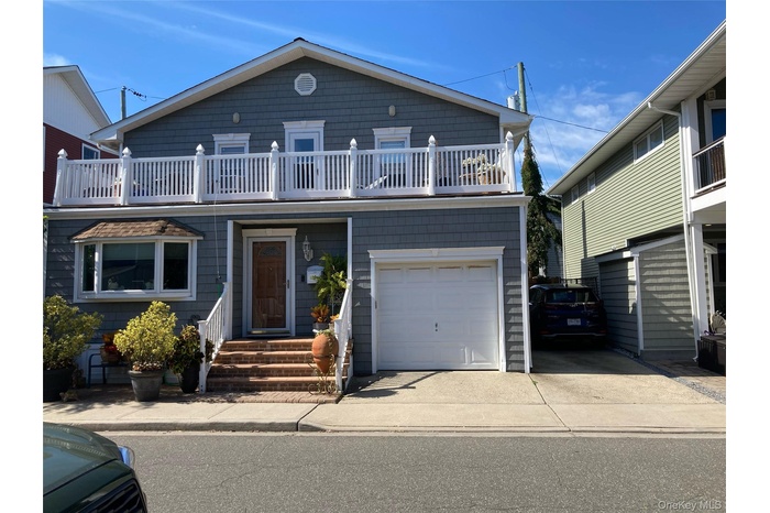 View of front of property with a garage, a balcony, and concrete driveway