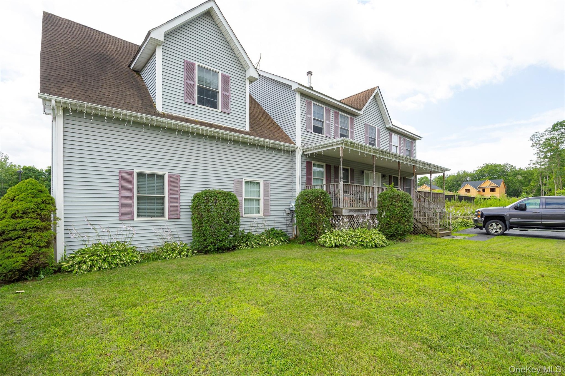 View of side of property featuring a porch, a yard, and a shingled roof