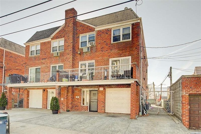 View of front of home with an attached garage, a chimney, driveway, and brick siding