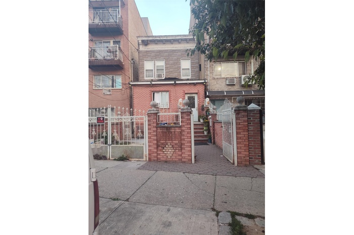 View of front of property with a gate, a fenced front yard, and brick siding