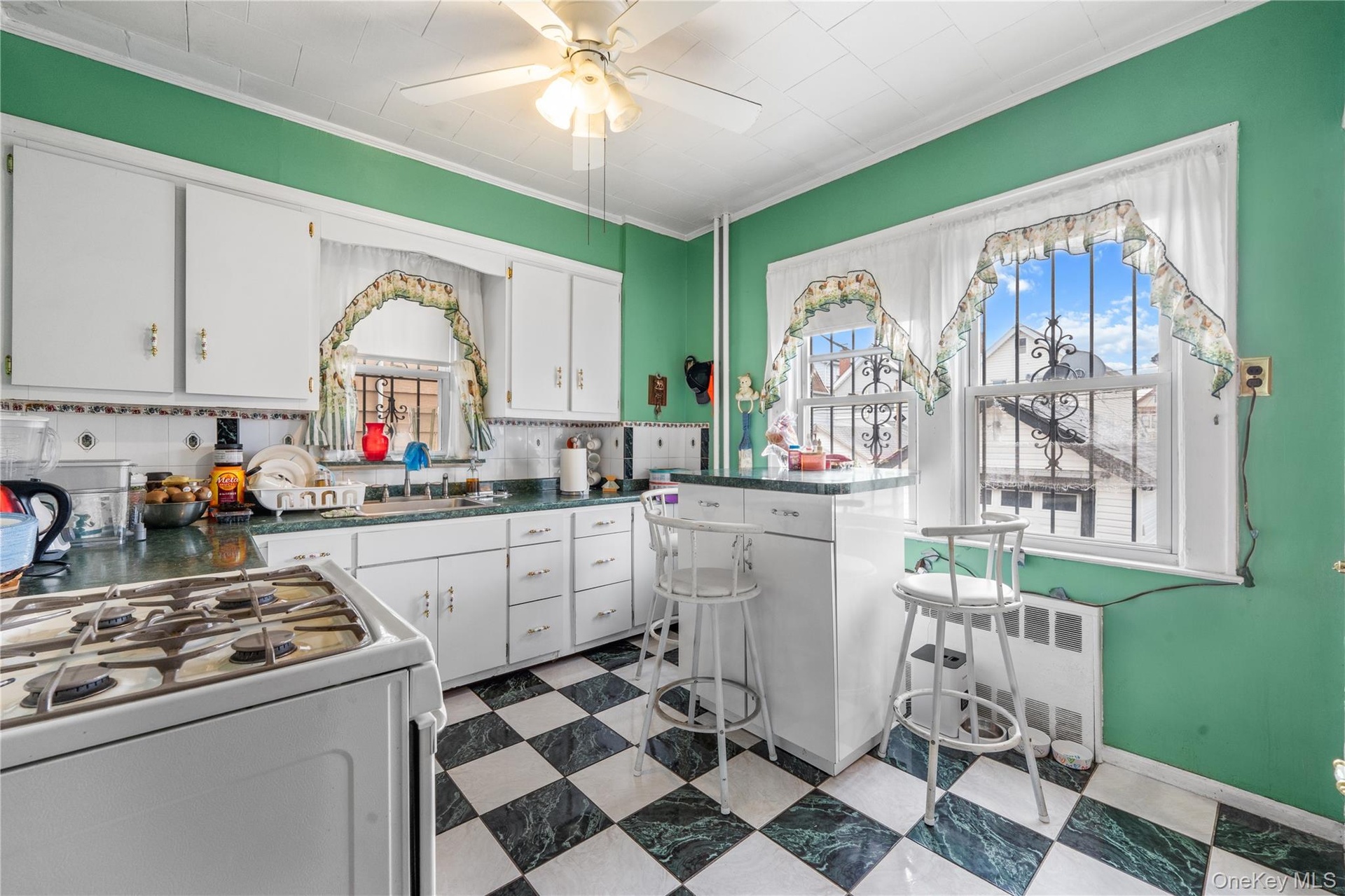 Kitchen with white range with gas stovetop, white cabinets, dark flooring, dark countertops, and crown molding