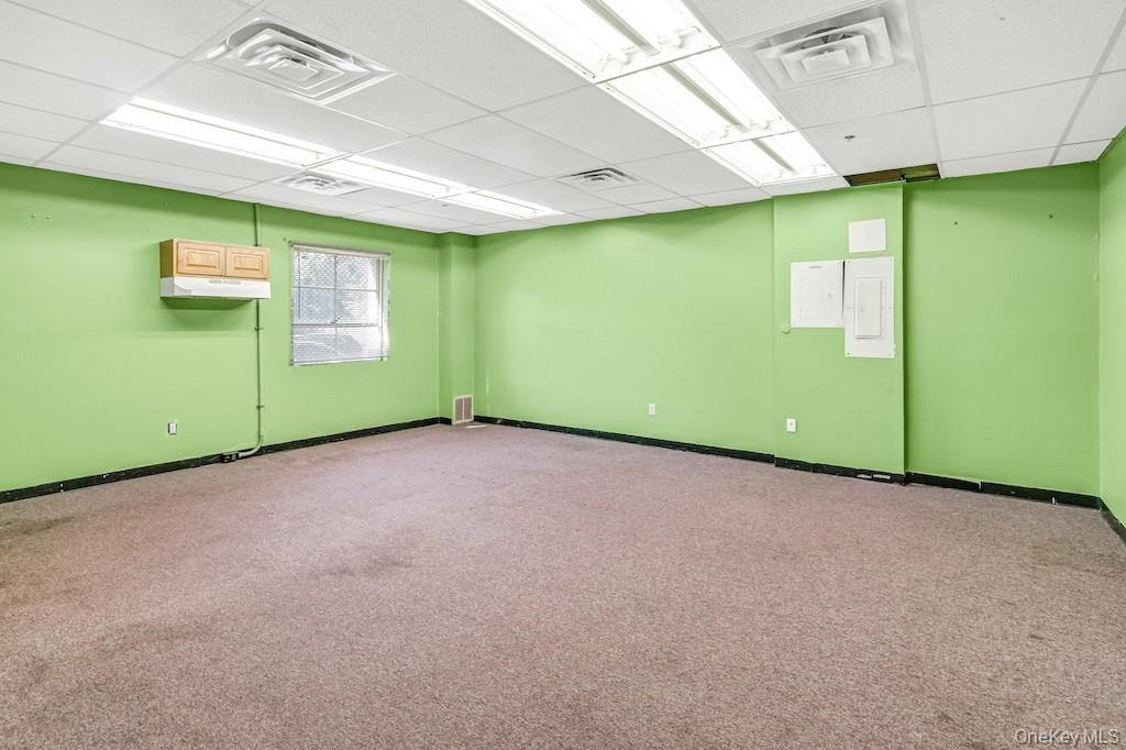 Carpeted empty room with a drop ceiling and baseboards