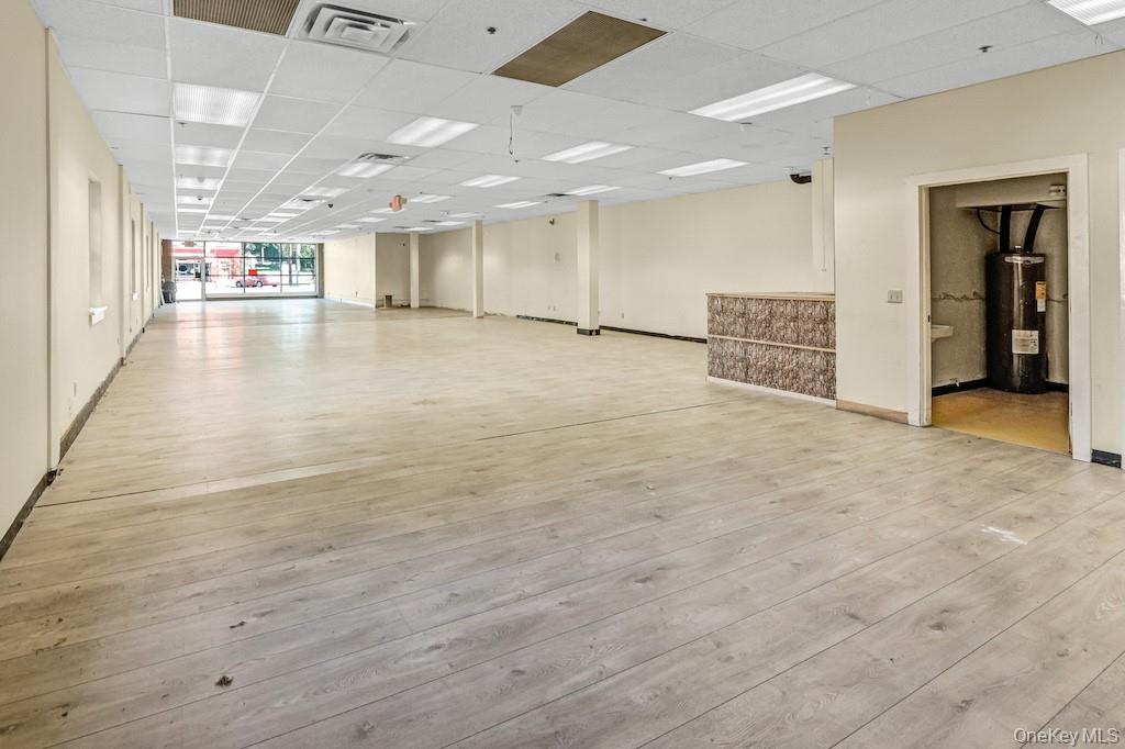 Unfurnished room with a drop ceiling, light wood-style flooring, and electric water heater