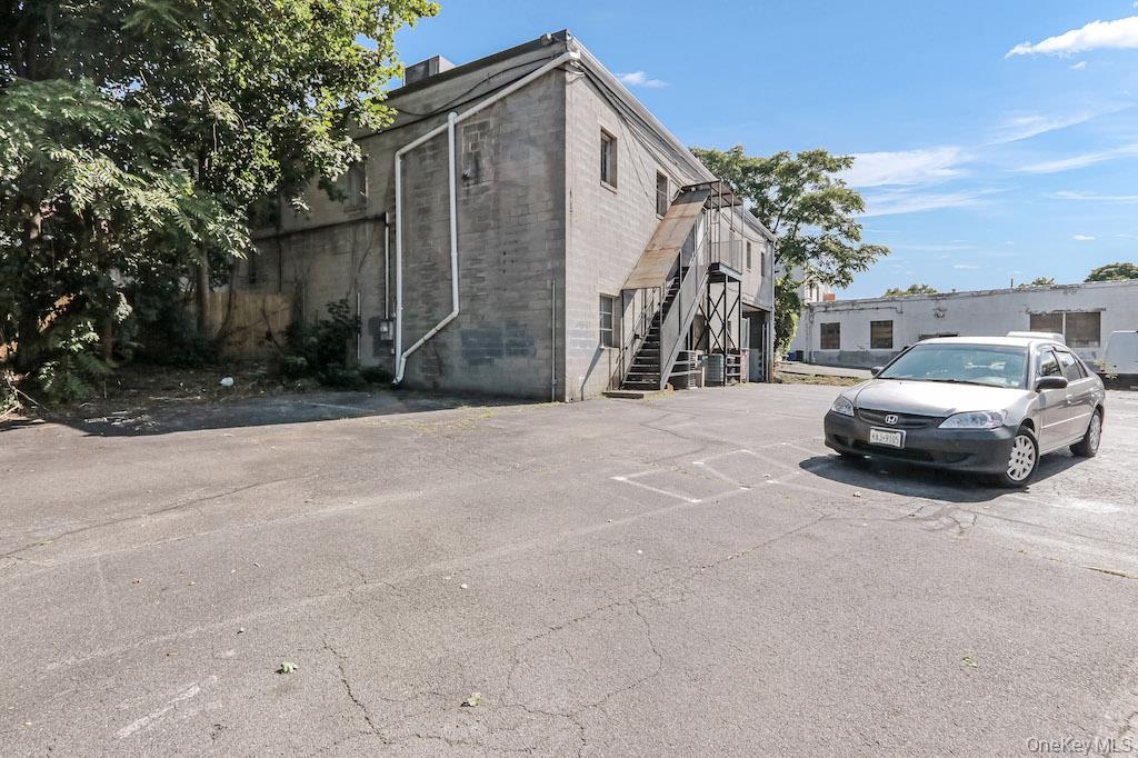 View of side of home with stairway, uncovered parking, and concrete block siding