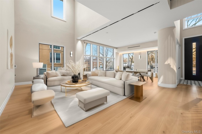 Living area with plenty of natural light, light wood finished floors, and a high ceiling