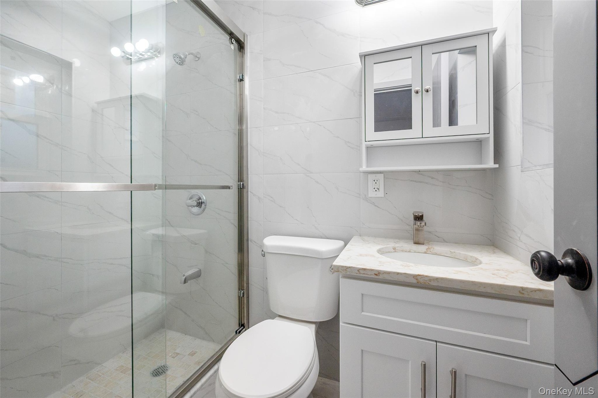 Full bathroom featuring tile walls, a marble finish shower, and vanity