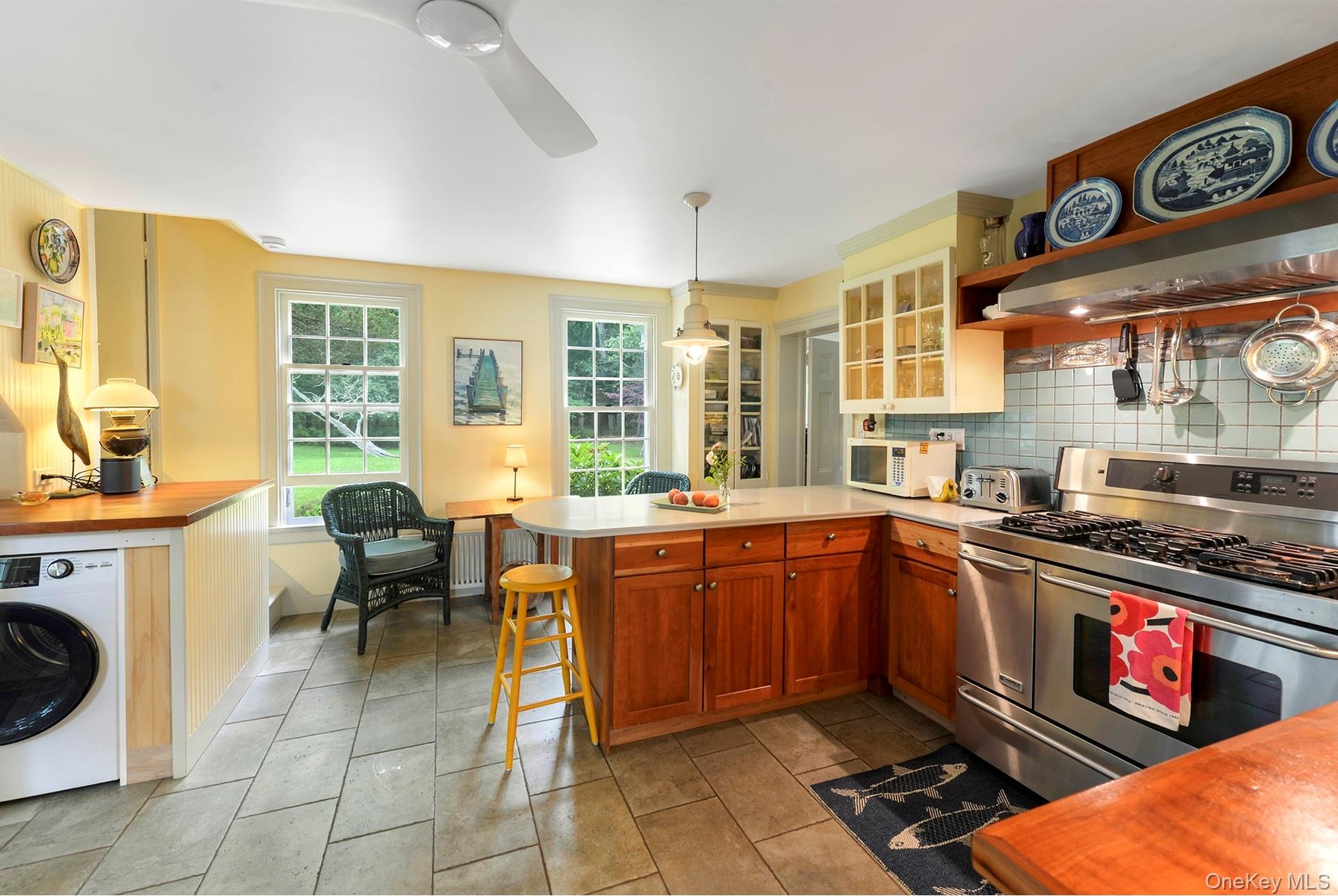 Kitchen featuring range with two ovens, washer / dryer,microwave, custom exhaust hood, and a peninsula