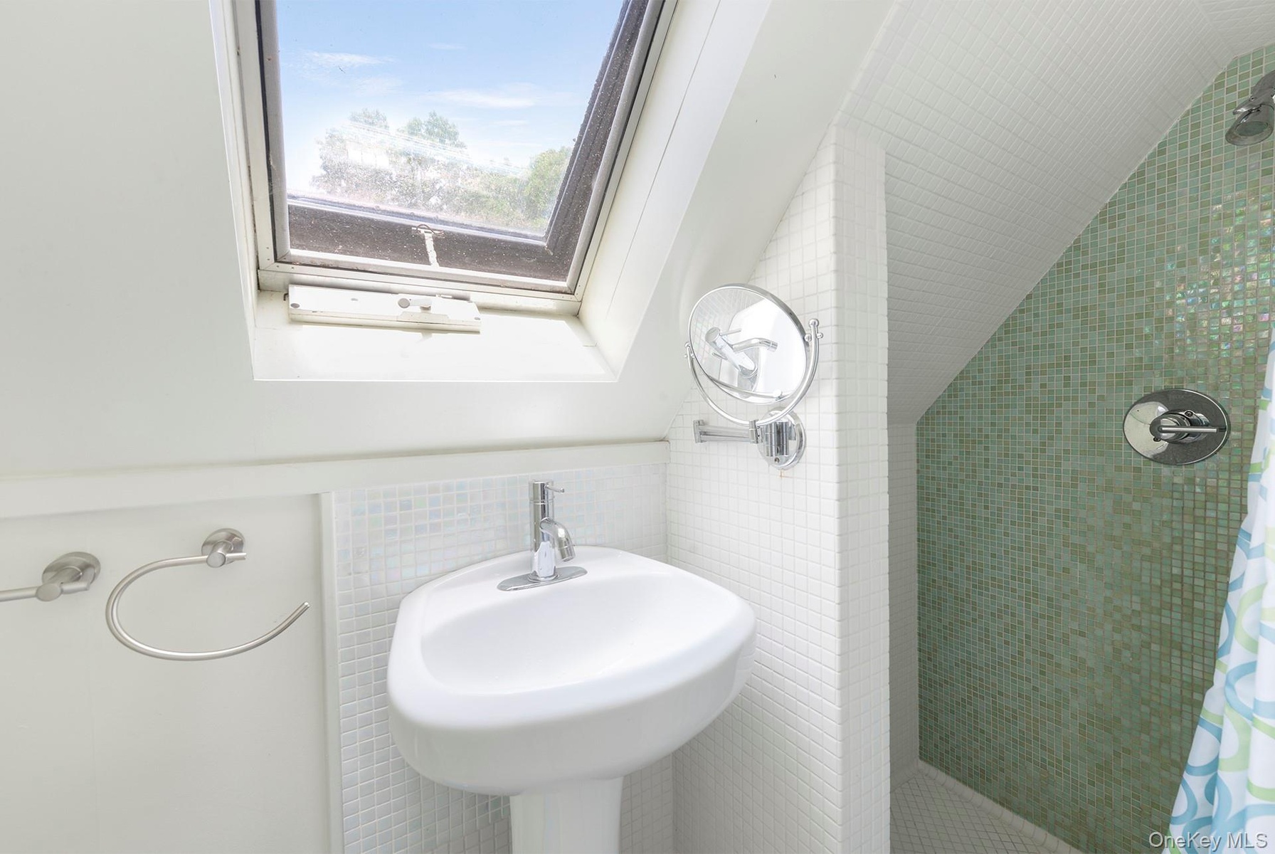 Full bathroom with tile walls, a tile shower, and a skylight
