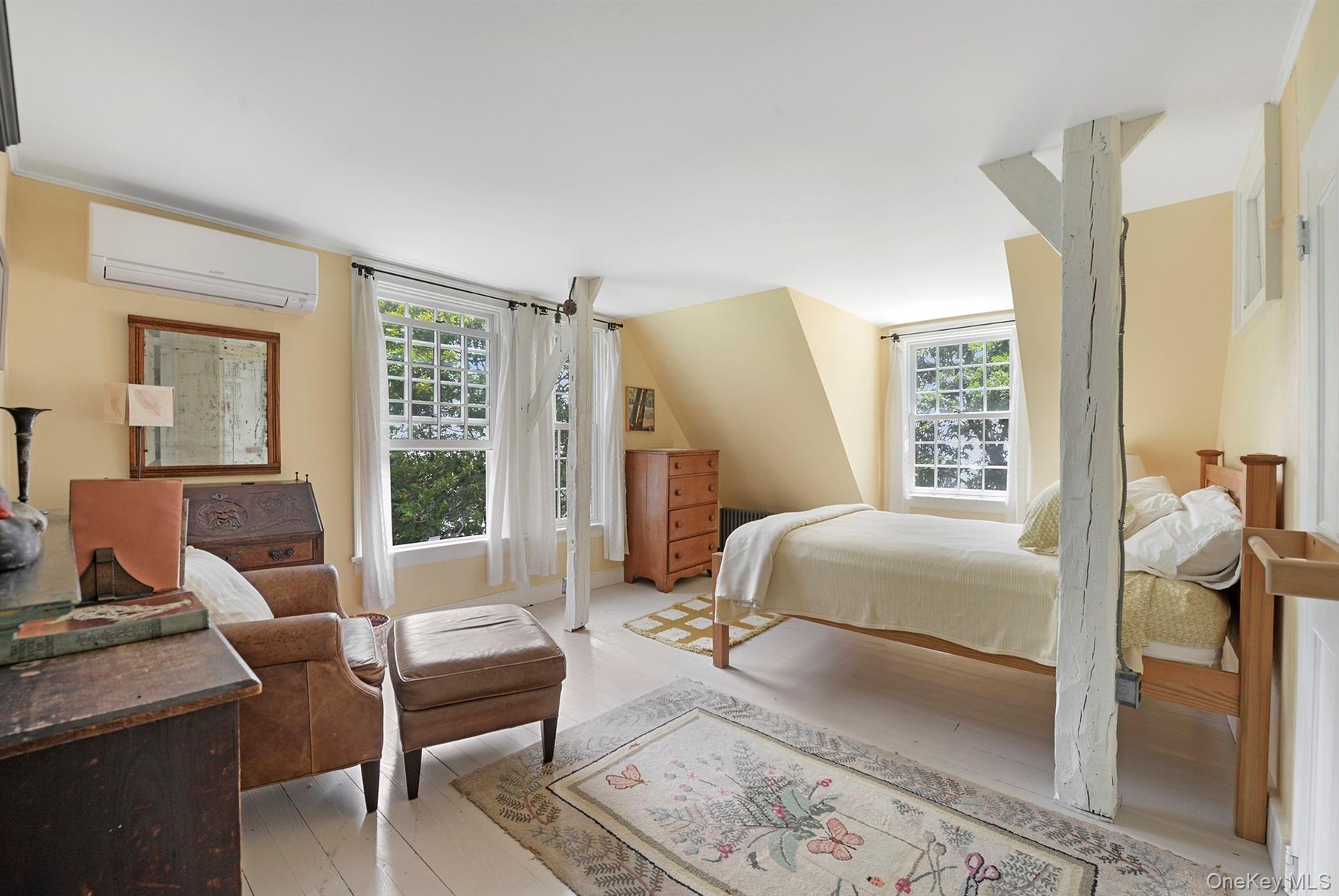 Bedroom with an AC wall unit, multiple windows, and light wood-type flooring