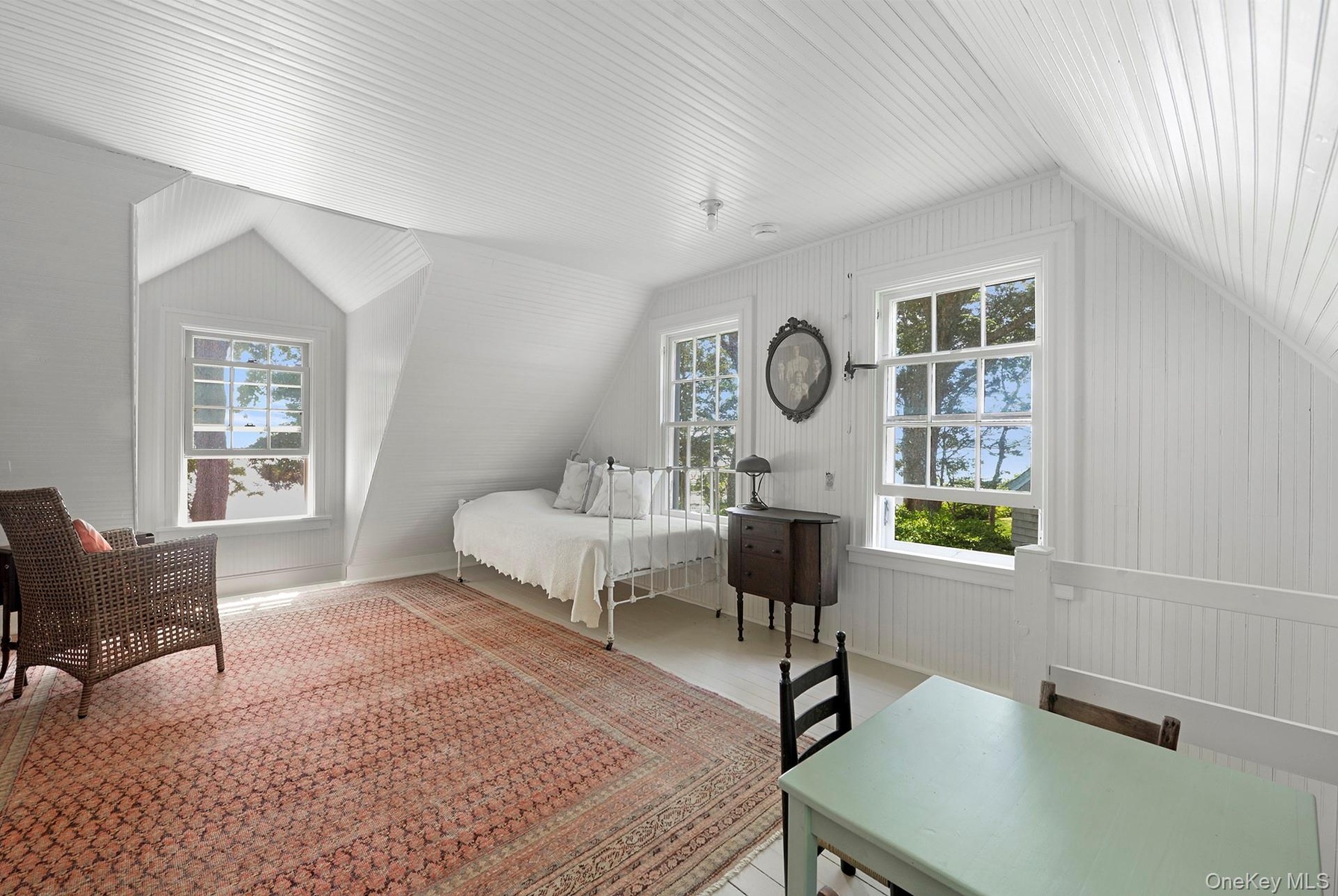 Bedroom with vaulted ceiling, multiple windows, and wood finished floors
