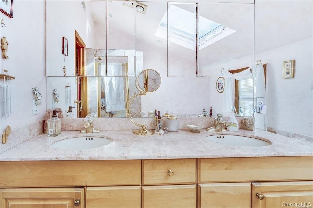 Bathroom featuring a skylight, double vanity, and healthy amount of natural light