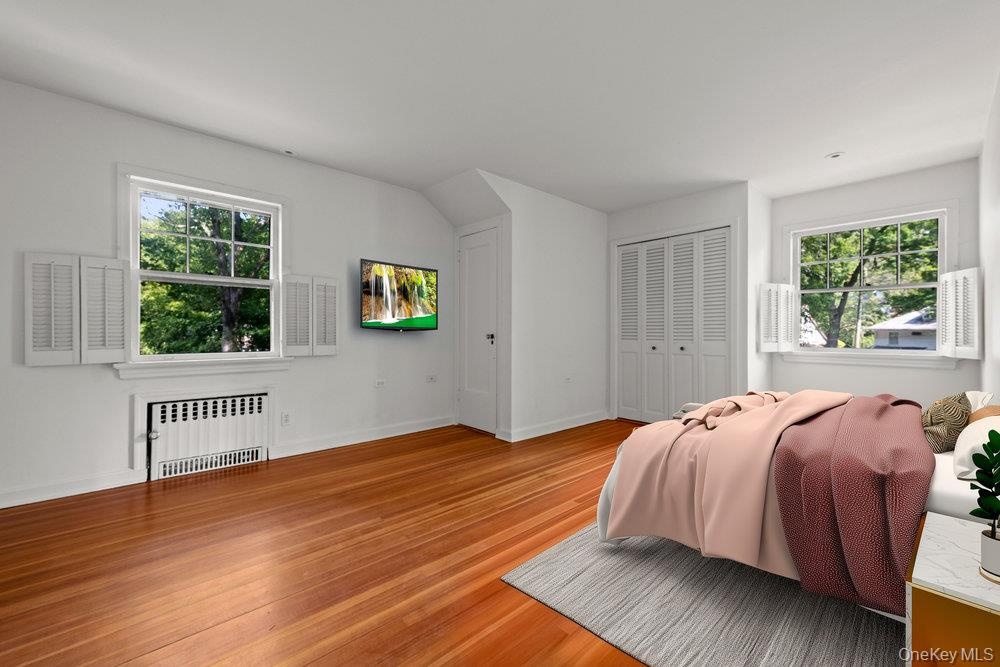 Bedroom with radiator heating unit, wood finished floors, and a closet