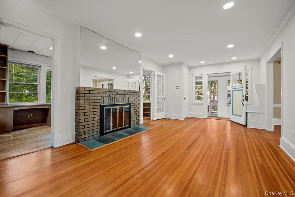 Unfurnished living room featuring hardwood / wood-style floors, a brick fireplace, and recessed lighting