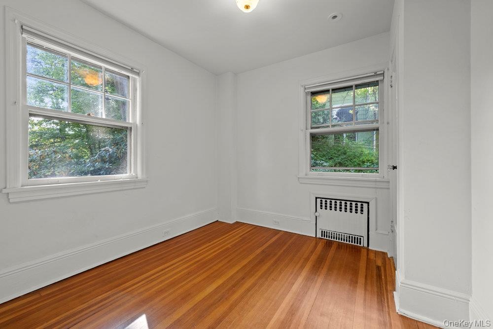 Spare room featuring radiator heating unit and light wood-type flooring