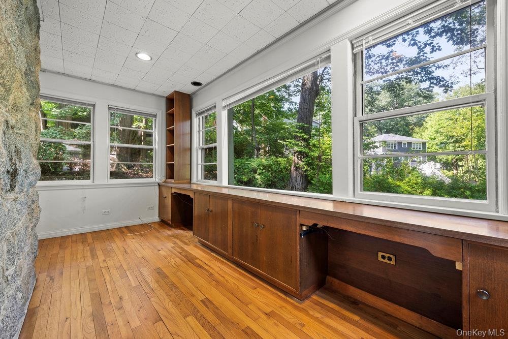 Unfurnished sunroom with built in desk and view of scattered trees