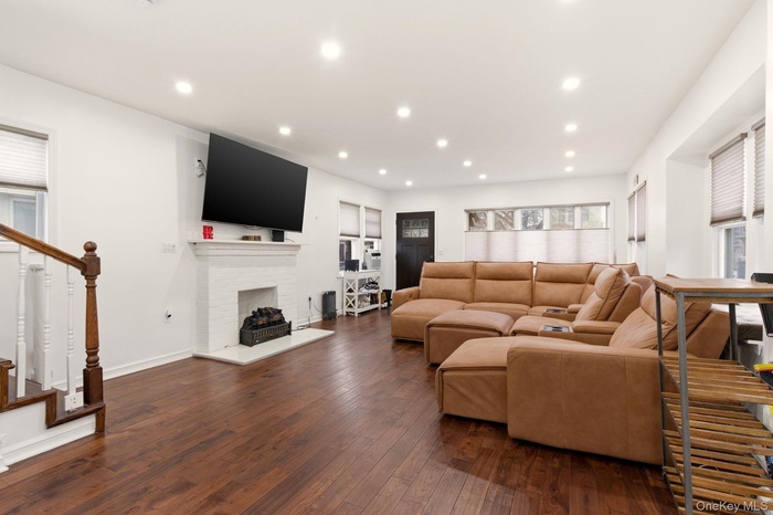 Living room featuring dark wood-style floors, a fireplace, and recessed lighting