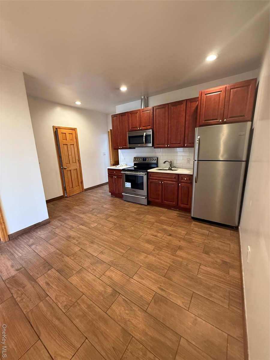 Kitchen featuring refrigerator, light countertops, stainless steel range with electric cooktop, wood finished floors, and recessed lighting