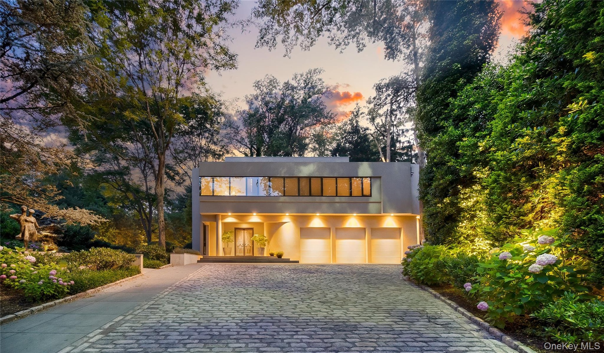 Contemporary home with stucco siding, decorative driveway, and a garage