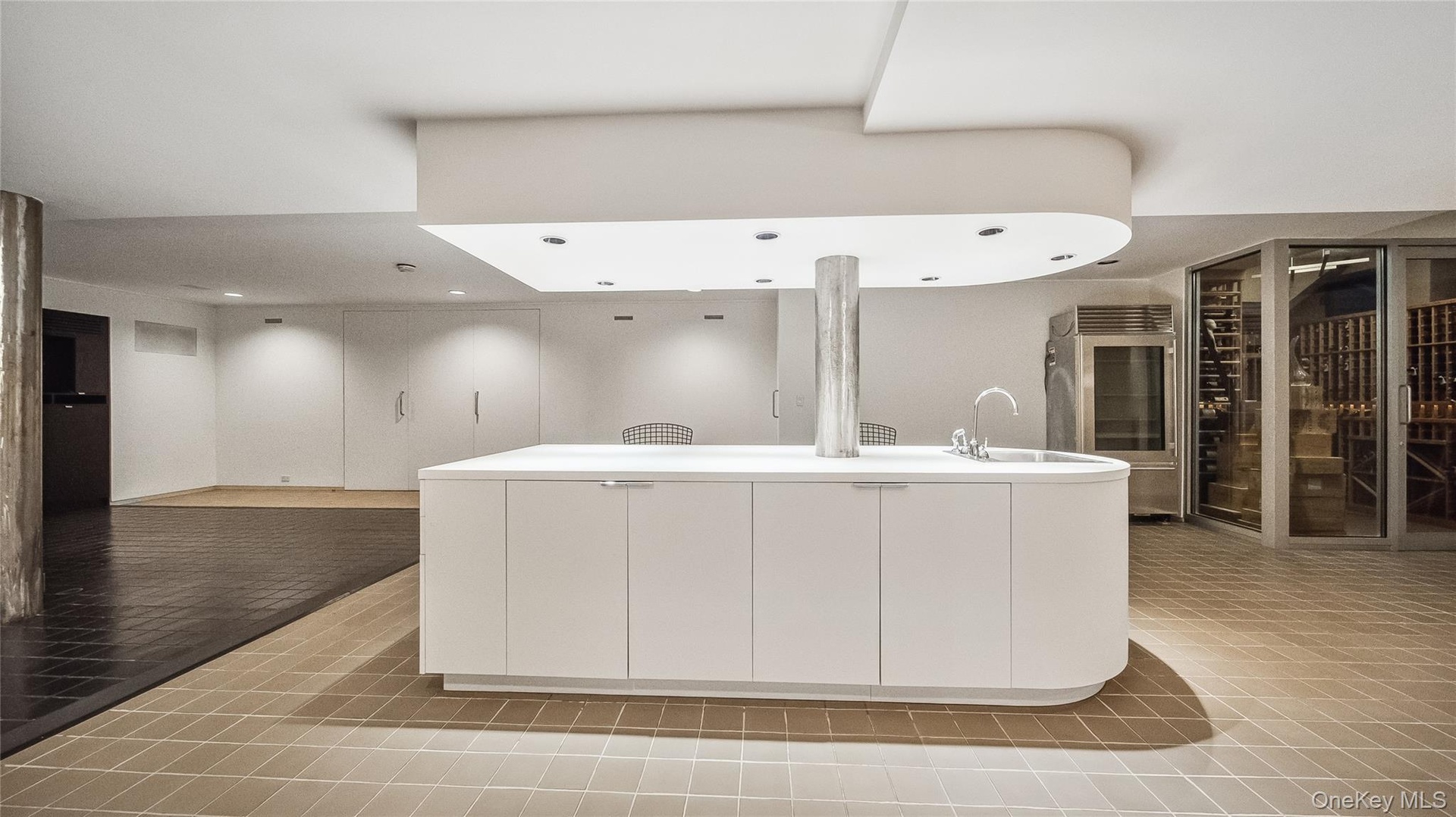 Kitchen with modern cabinets, white cabinetry, light countertops, and an island with sink