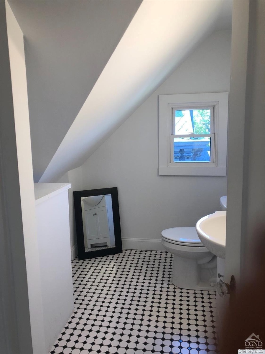 Bathroom with vaulted ceiling, light flooring, and vanity