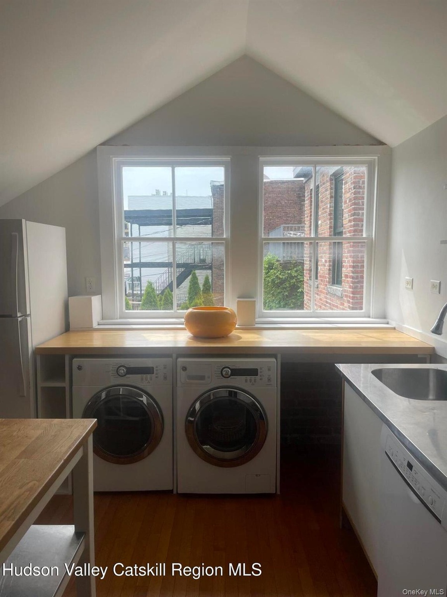 Laundry area with lofted ceiling, washing machine and clothes dryer, healthy amount of natural light, and dark wood-style floors