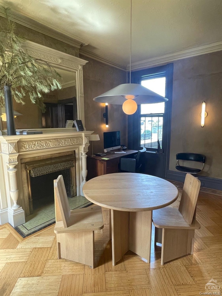 Dining space with a fireplace with raised hearth and crown molding