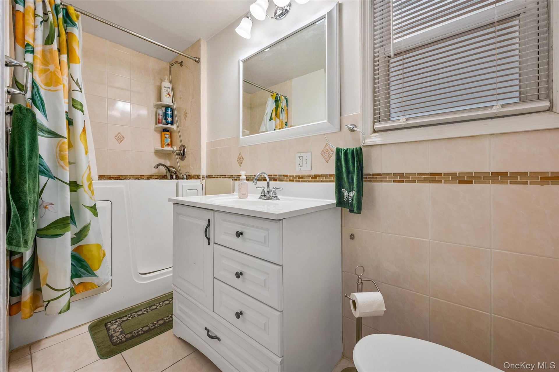 Full bath with tile walls, vanity, shower / bath combo, and light tile patterned floors
