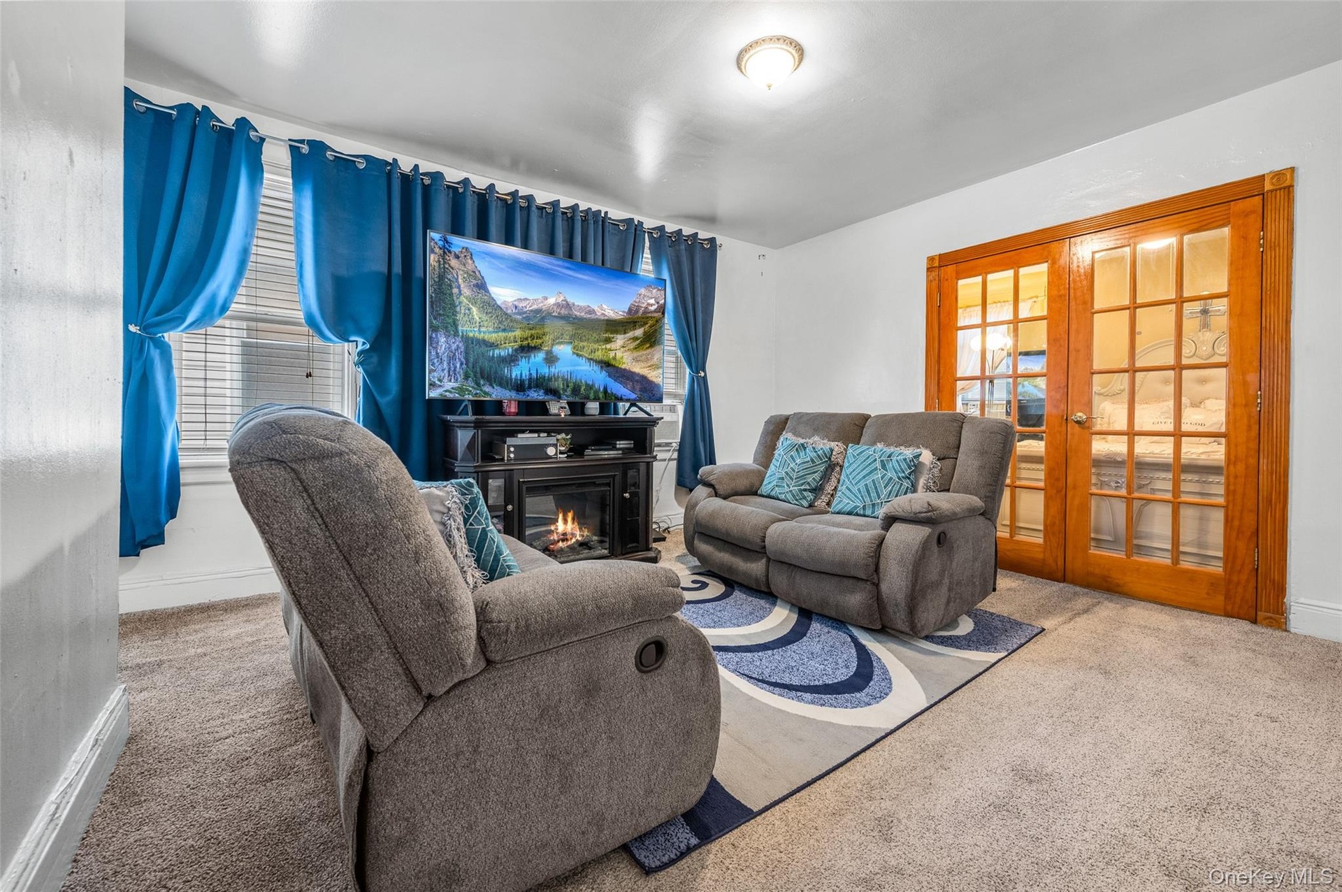 Living area with carpet flooring, french doors, and a glass covered fireplace