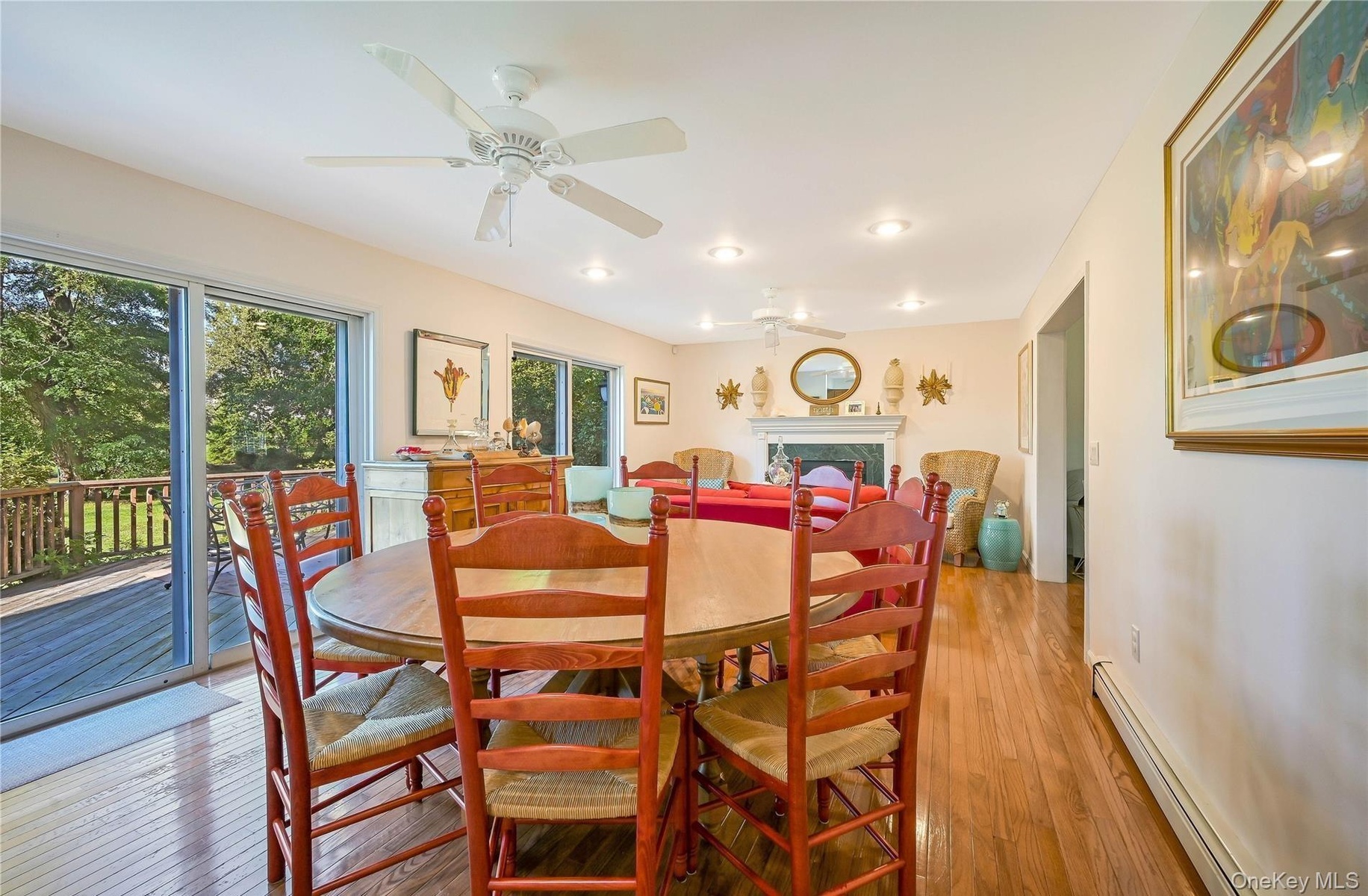 Dining space with baseboards, ceiling fan, a baseboard radiator, light wood-style flooring, and a fireplace