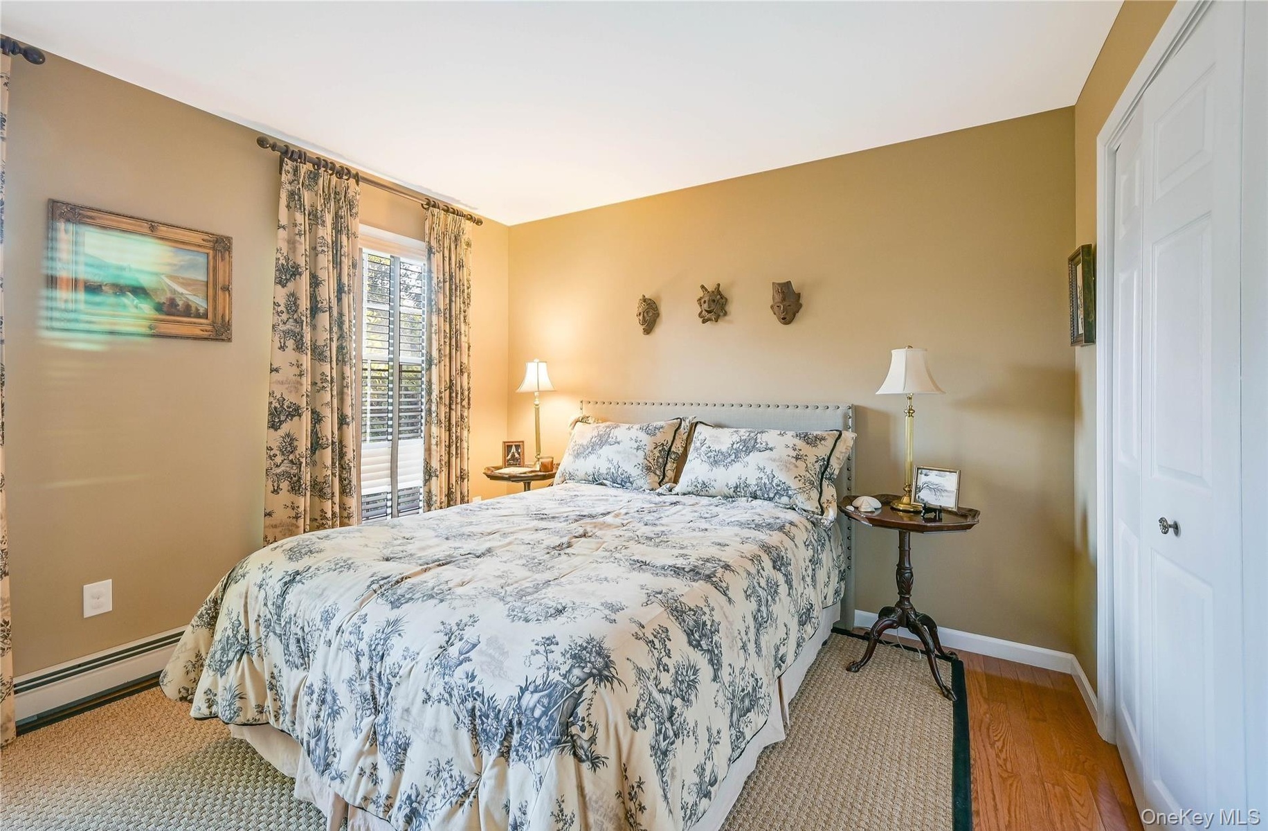 Bedroom with baseboards, wood finished floors, and baseboard heating