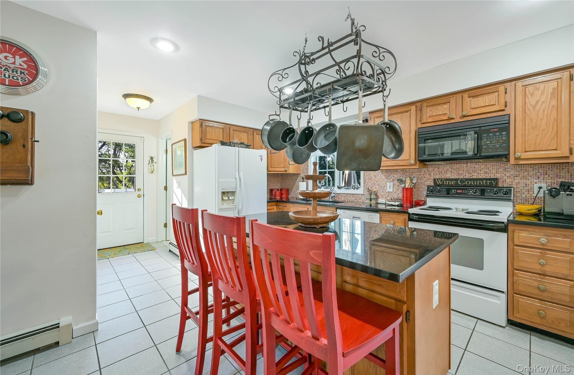 Kitchen featuring white appliances, light tile patterned floors, a center island, backsplash, and baseboard heating
