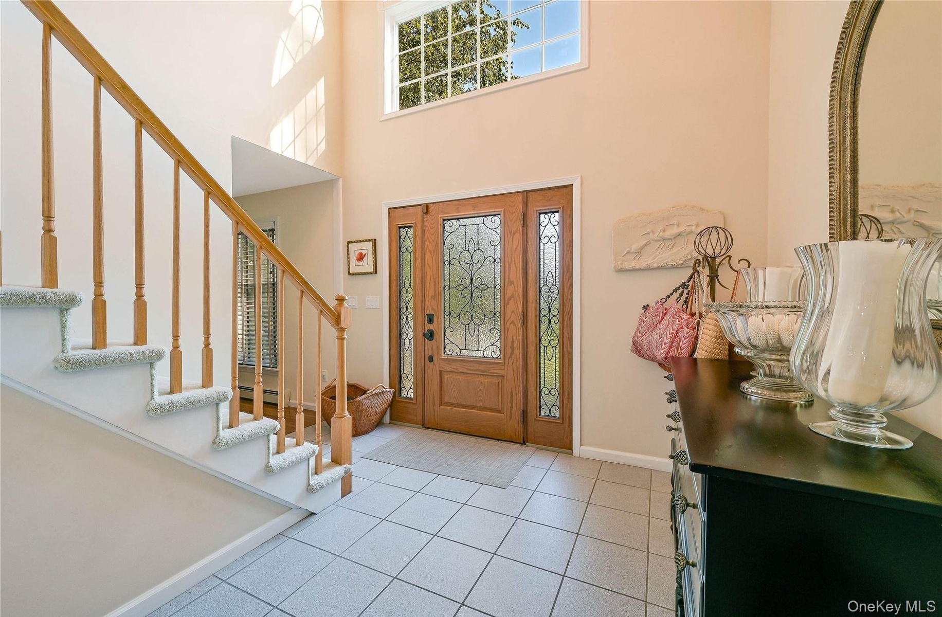 Entrance foyer featuring a towering ceiling, stairs, light tile patterned floors, baseboards, and a baseboard heating unit