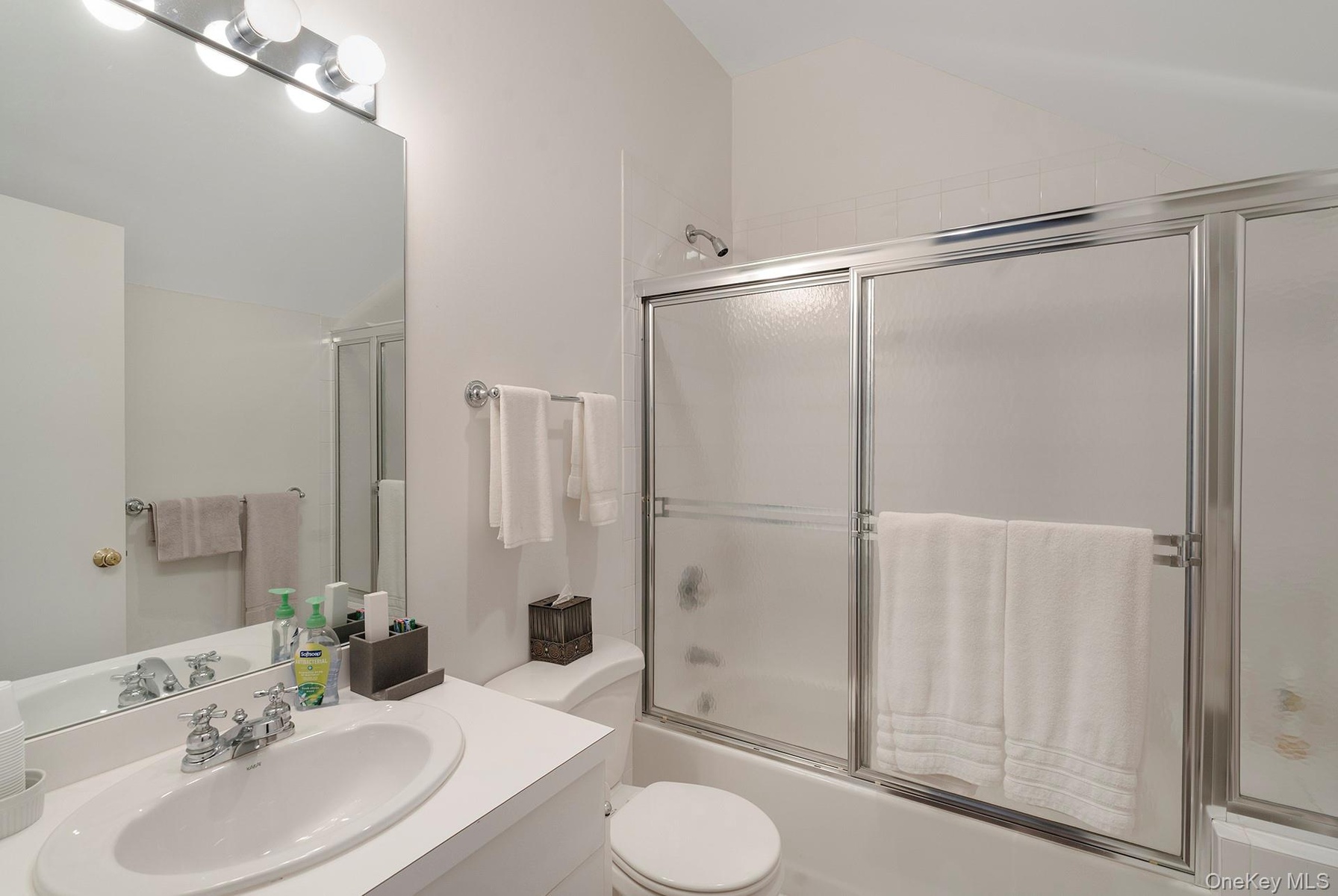 Bathroom with vanity, enclosed tub / shower combo, and lofted ceiling