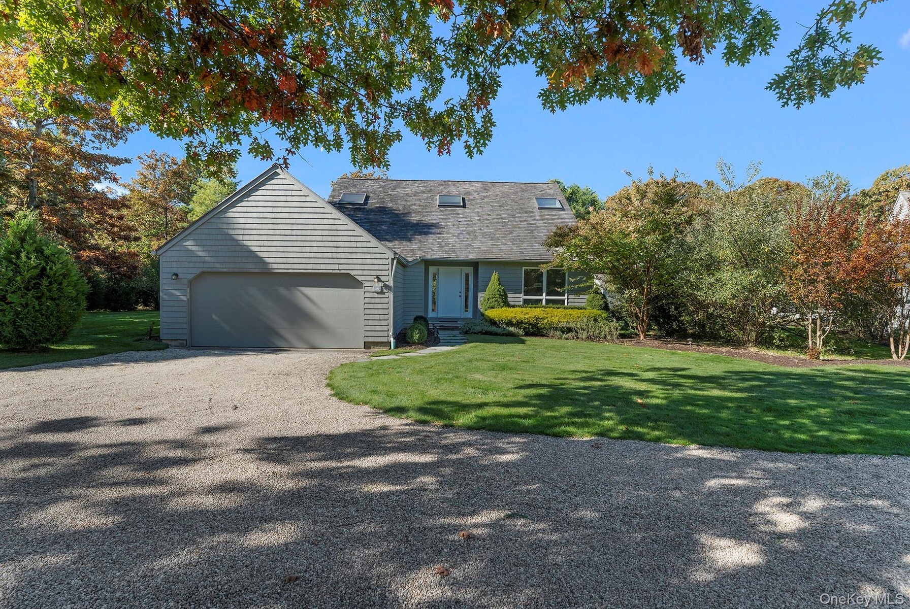 View of front of property featuring driveway, a front yard, a garage, and a shingled roof