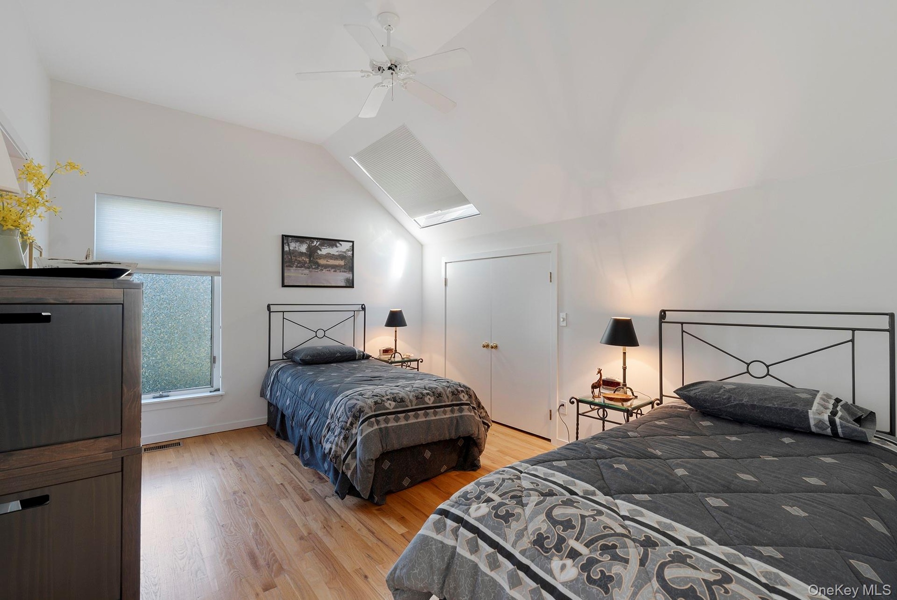 Bedroom with lofted ceiling, light wood-type flooring, a ceiling fan, and a skylight