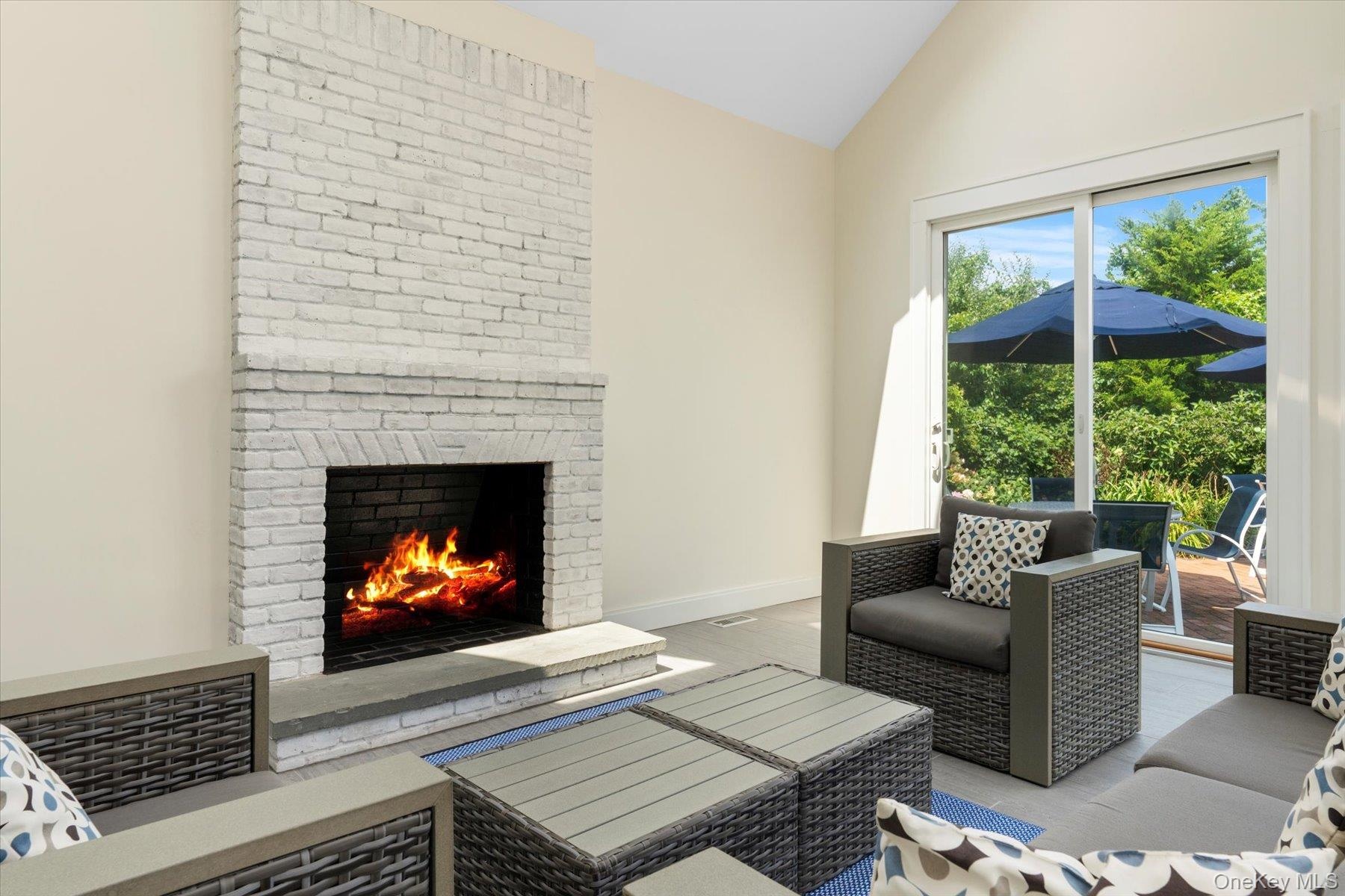 Living area featuring vaulted ceiling, a brick fireplace, and wood finished floors