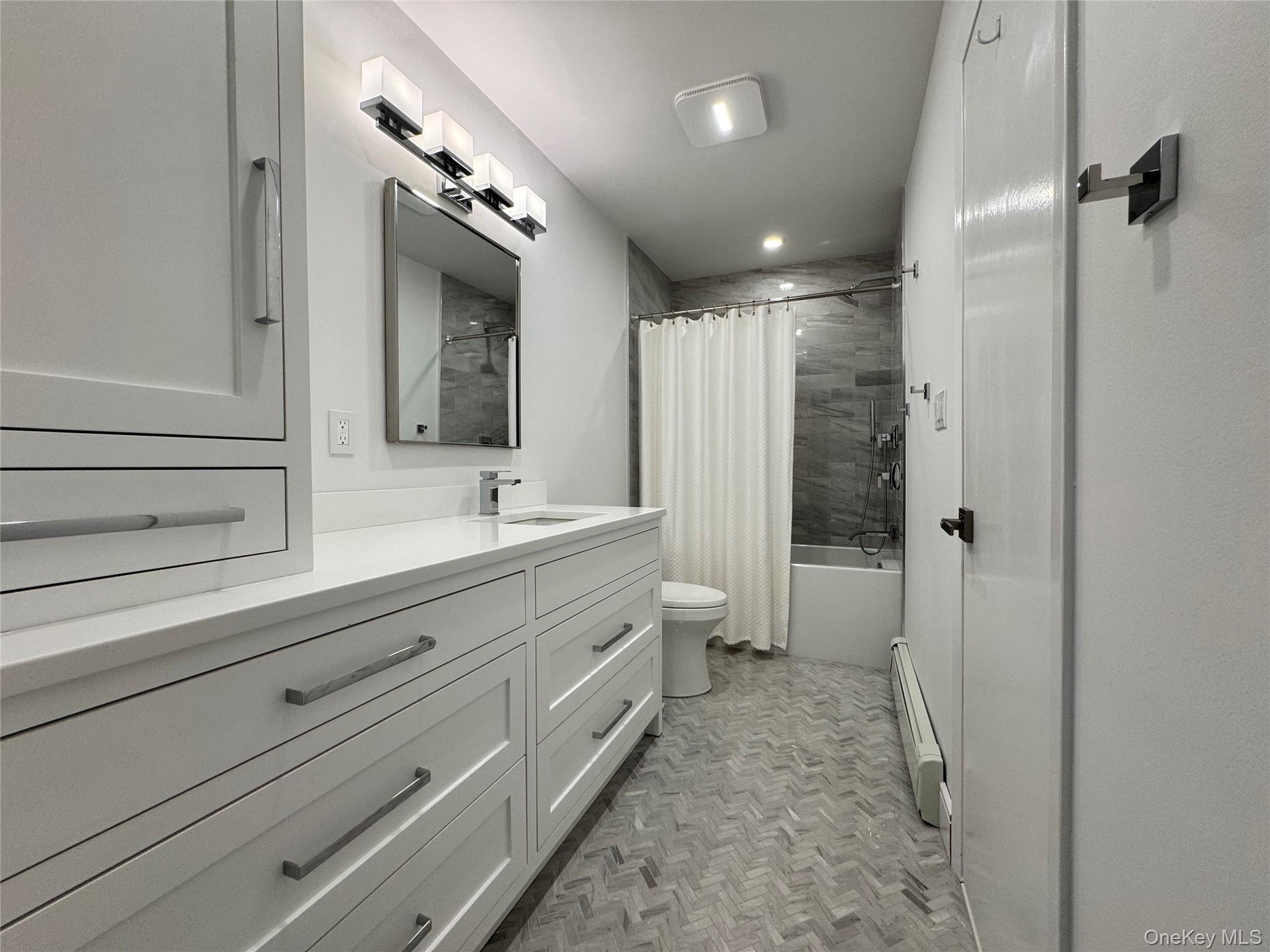 Bathroom with shower / bath combination with curtain, vanity, and baseboard heating