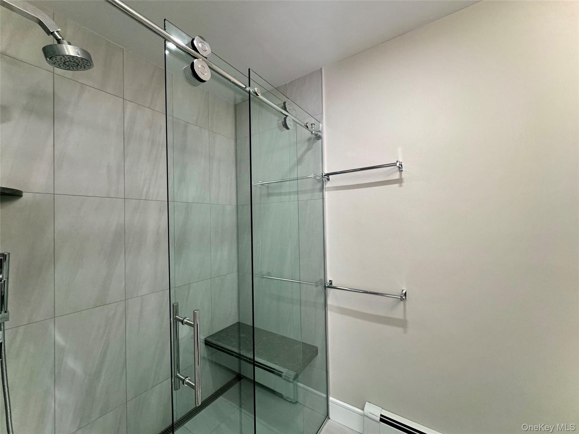 Full bathroom featuring a stall shower, a baseboard radiator, and tile patterned floors