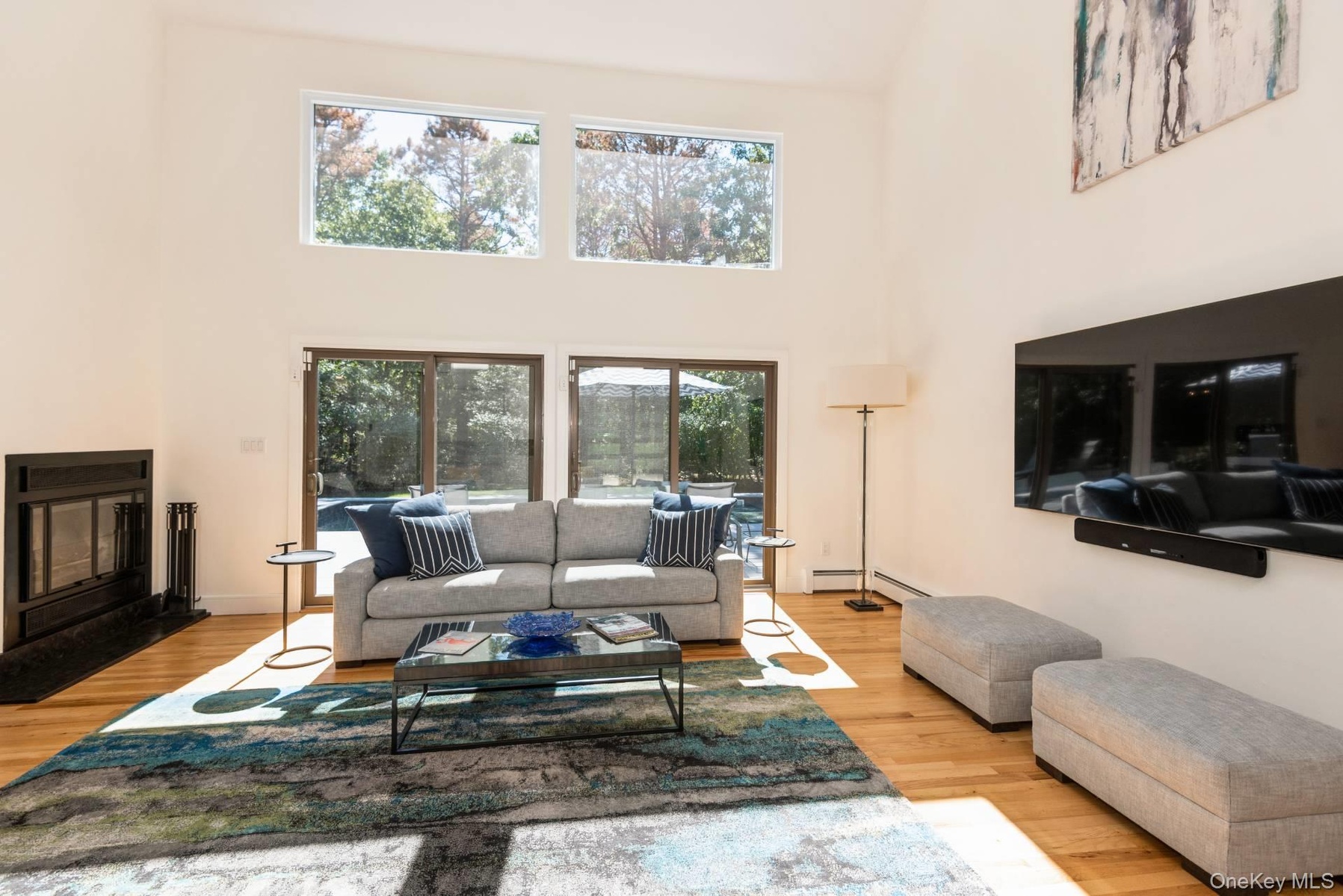 Living room featuring a high ceiling, a glass covered fireplace, and light wood-style flooring